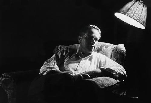 Porträt von William S. Heckscher, sitzend unter einer Stehlampe.